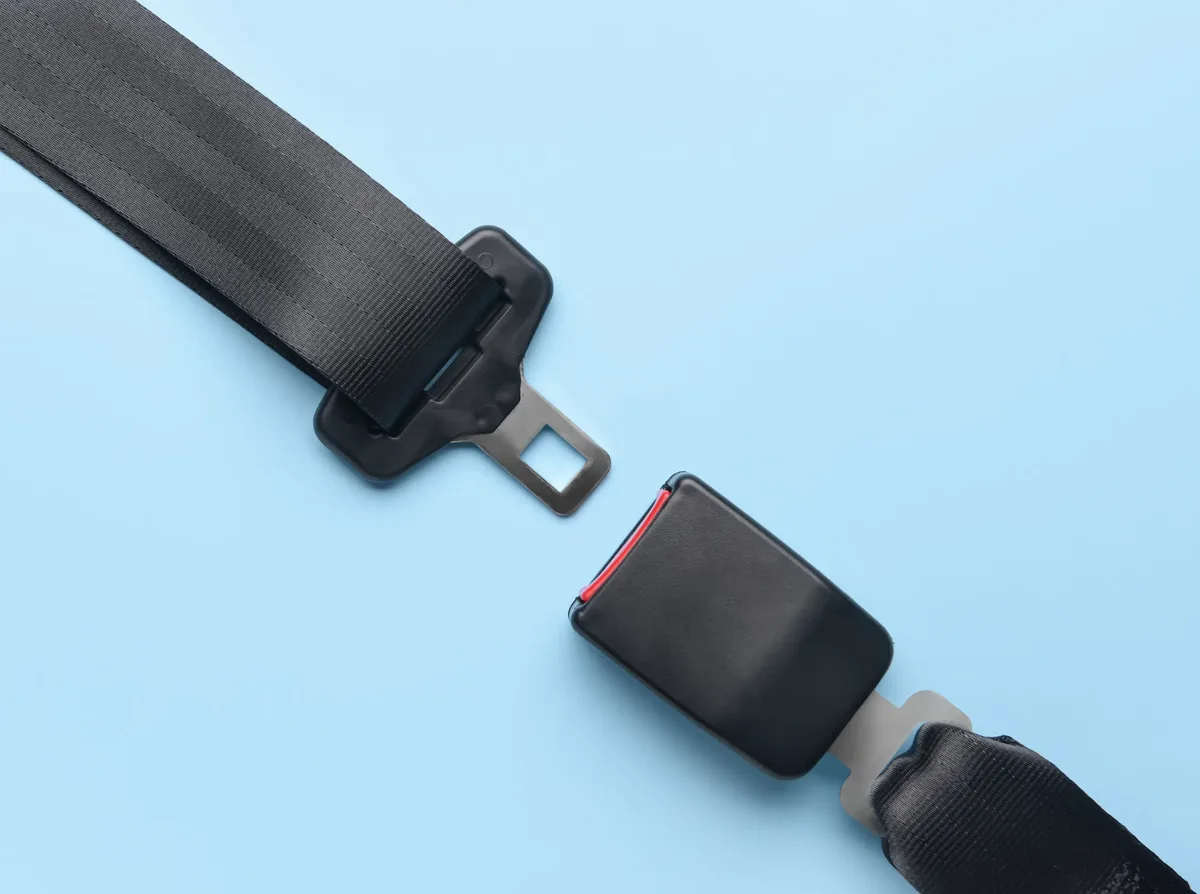 Seat belt tongue plate and buckle laid apart on a plain background showing the mating faces