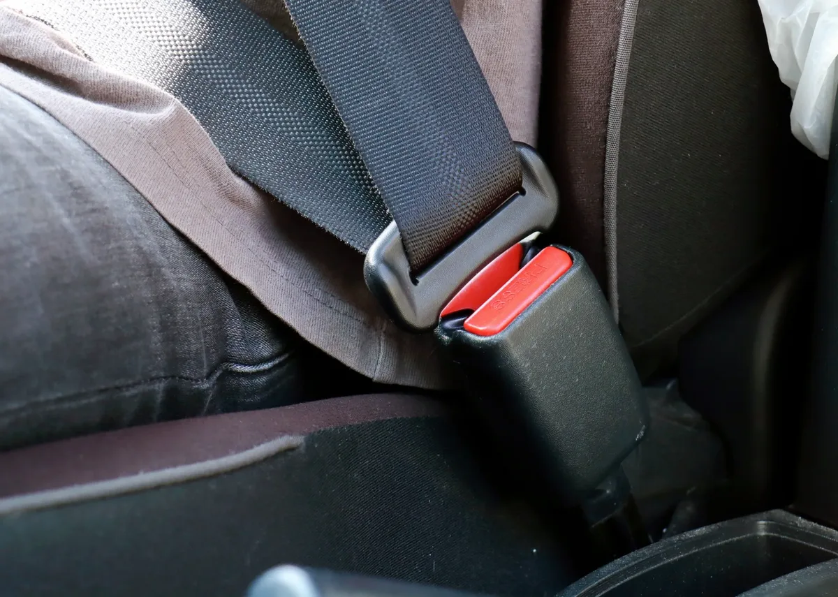 Rear vehicle seating position with the seat belt fastened into a buckle beside the seat cushion