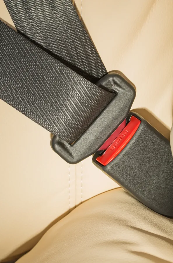 Seat belt webbing routed through a moulded guide loop above a light coloured vehicle seat
