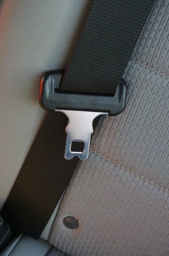 Metal seat belt tongue plate with rectangular locking slot held within a moulded webbing guide